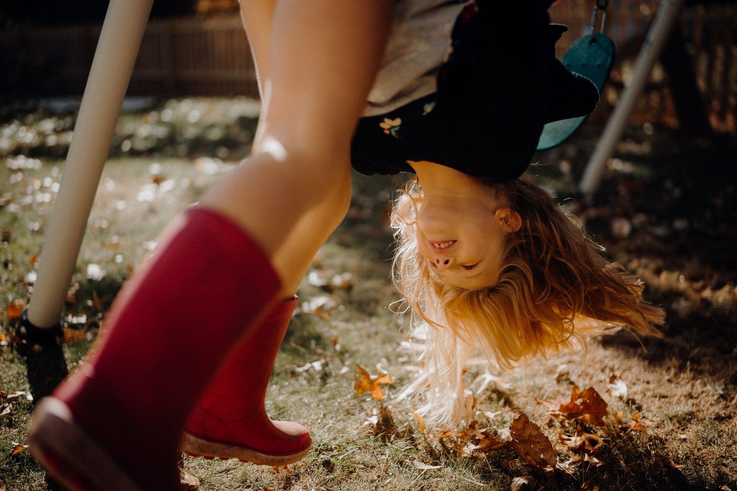 Red rain boots splash through autumn leaves in golden afternoon sunlight.