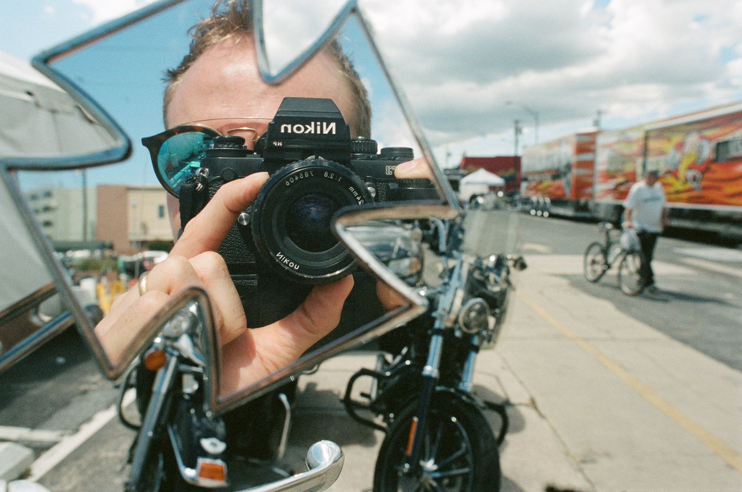 Photographer with sunglasses using Ricoh camera on motorcycle.