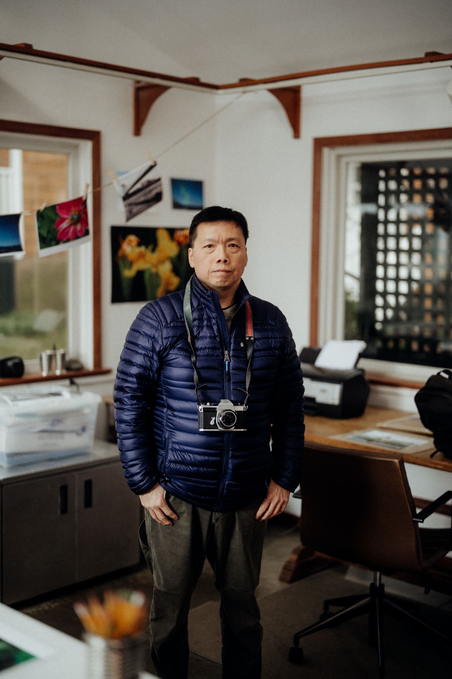 A photographer standing in an office space with camera equipment and artwork on the walls.