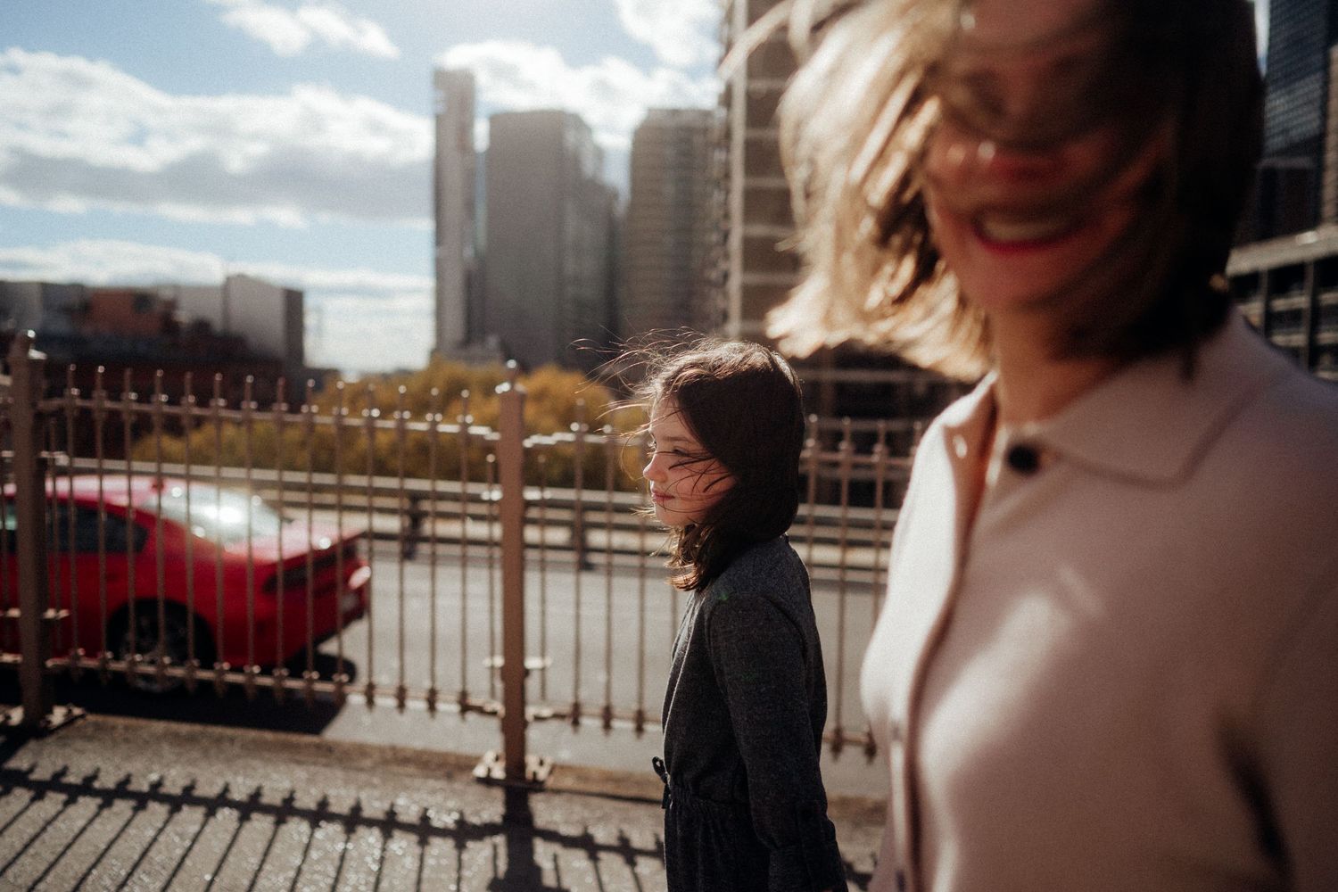 People walking and enjoying a rooftop terrace with city views and outdoor seating on a sunny day.