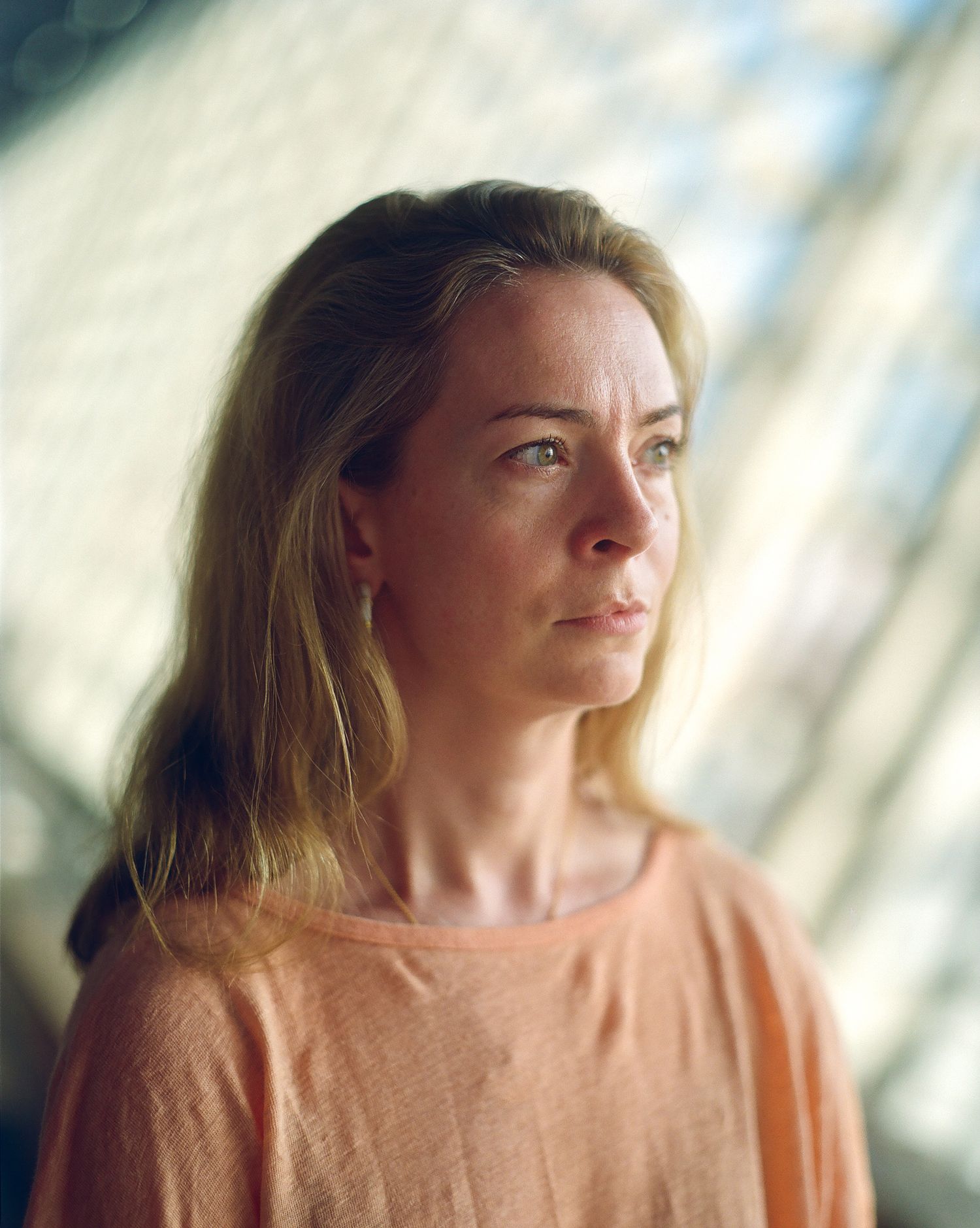 Contemplative portrait with natural window lighting casting diagonal shadows.
