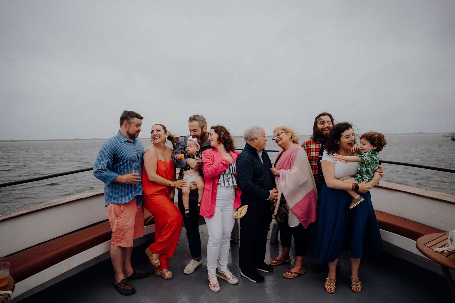 A group of people celebrating together on a boat deck against an overcast sky.