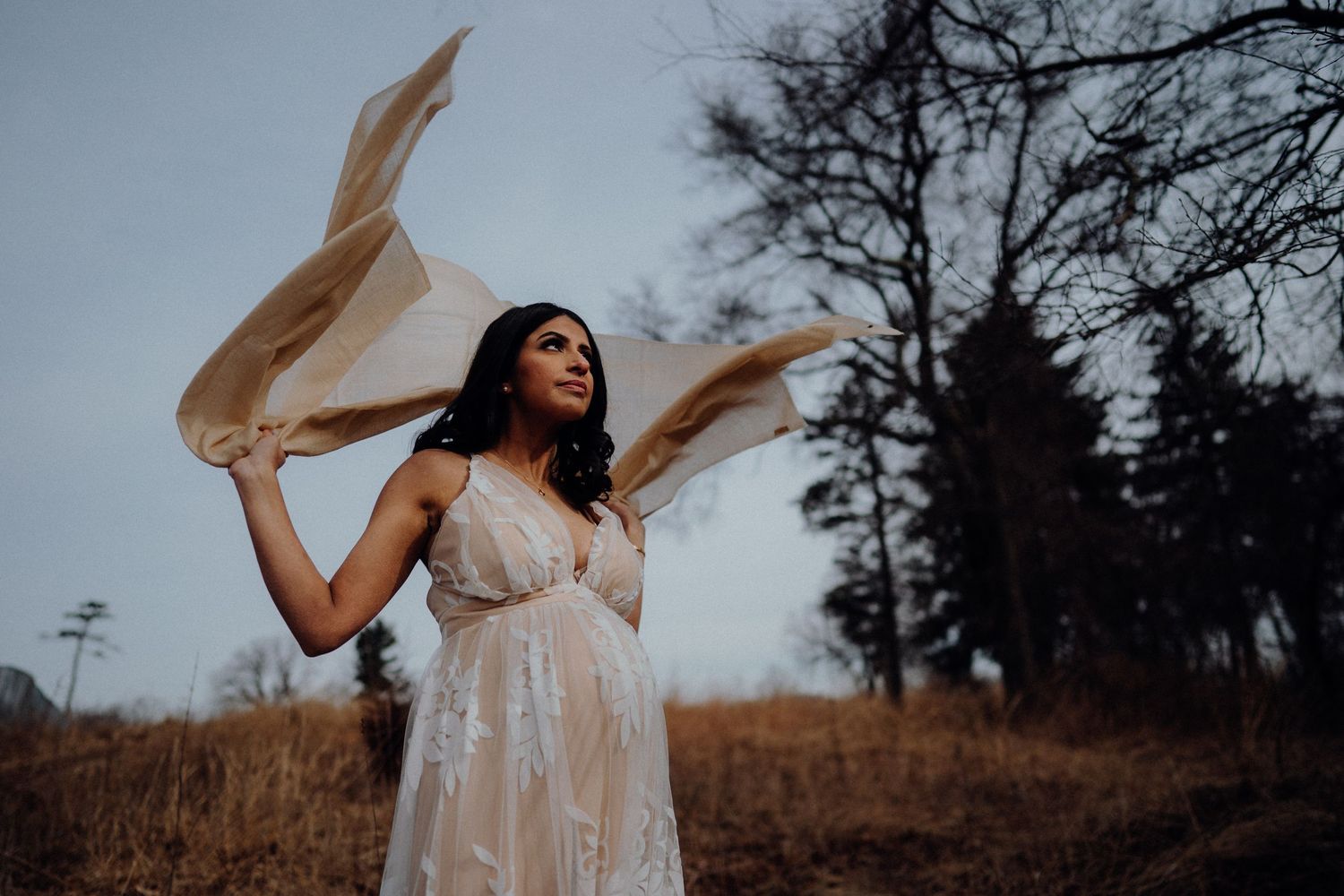 A flowing white dress catches the wind during a dramatic outdoor photo session.