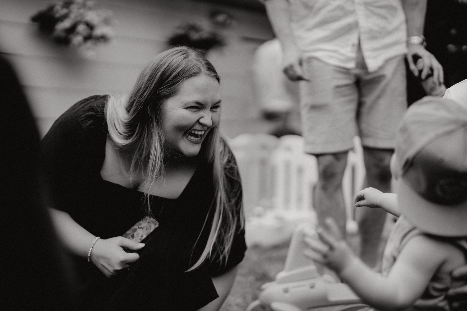 Black and white photo capturing genuine laughter at an outdoor social event.