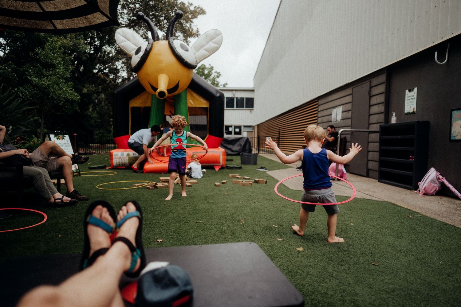 Children play outside near a yellow bounce house on a grassy area during a sunny day.