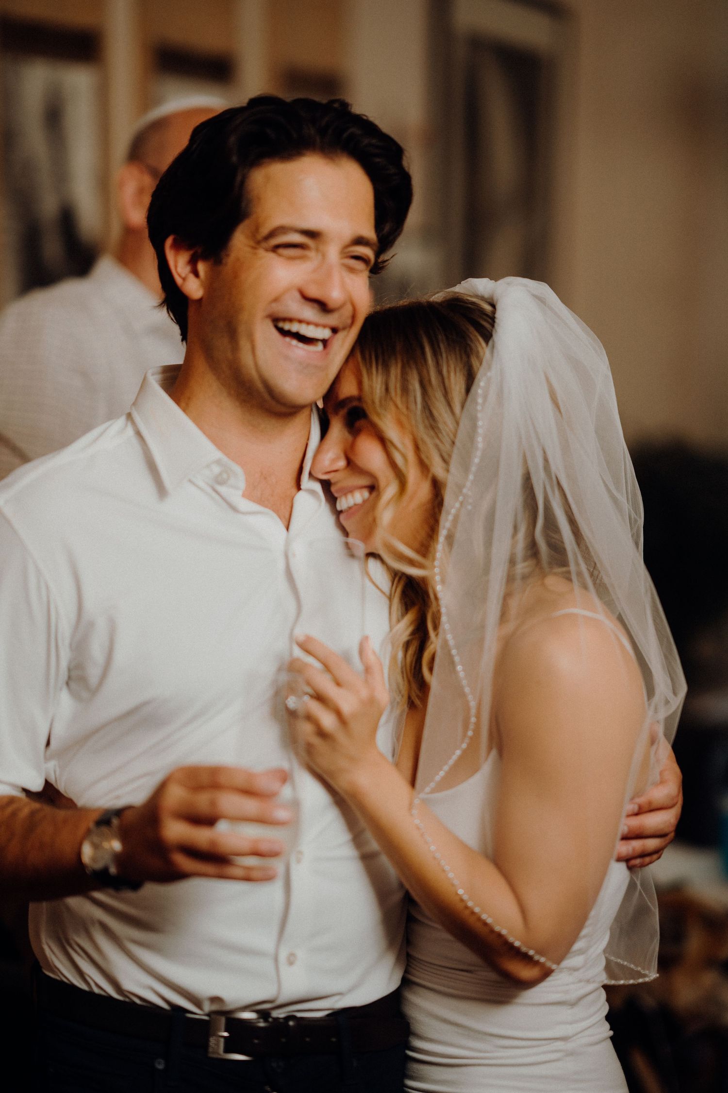 A joyful wedding couple shares an intimate laughing moment together.