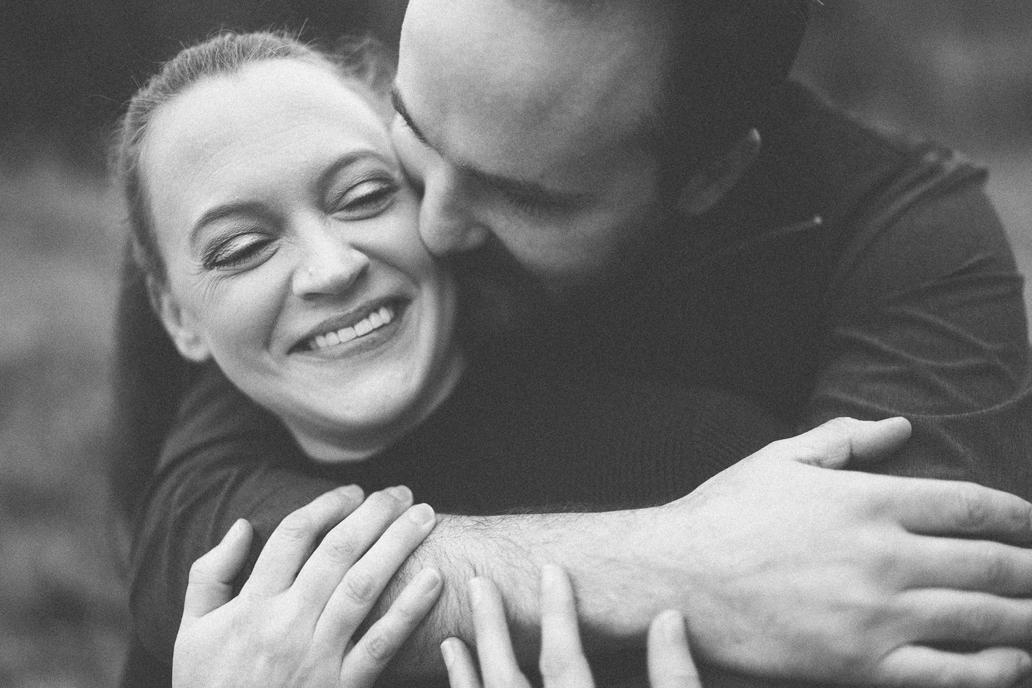 An intimate black and white portrait of a couple embracing and laughing together.