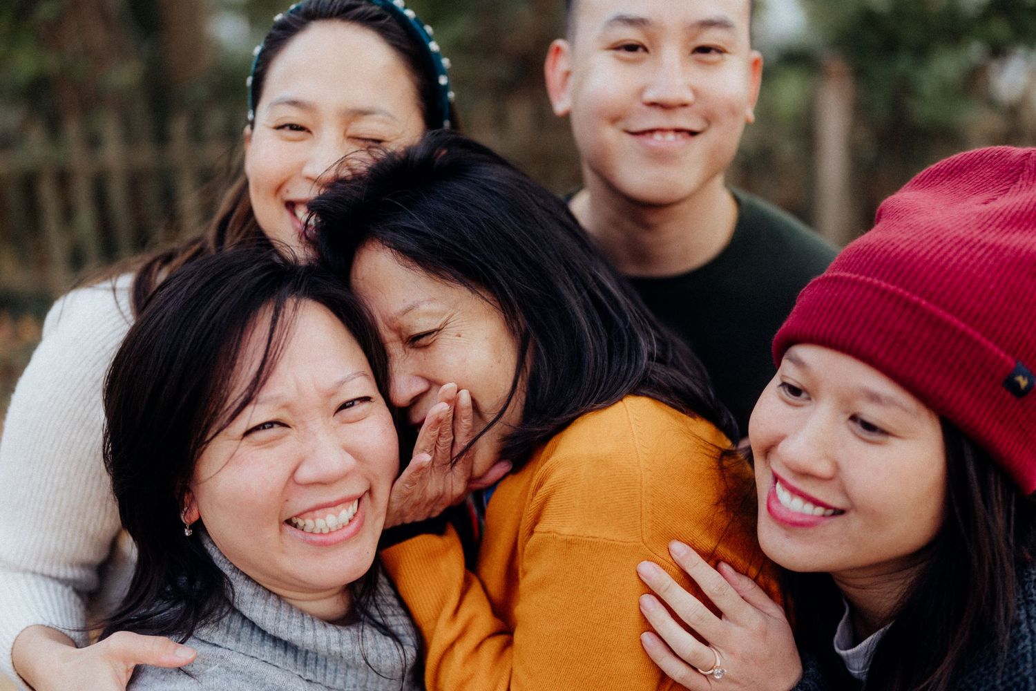 A group of friends laughing and hugging together while wearing winter clothing.