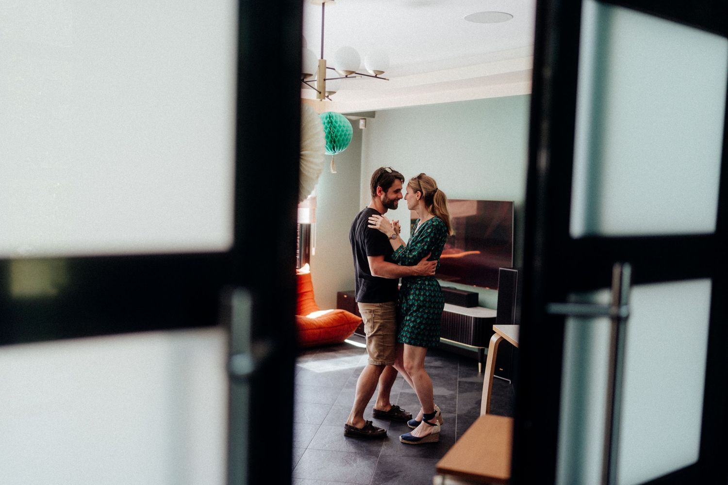 A couple embracing in a room viewed through a doorframe.