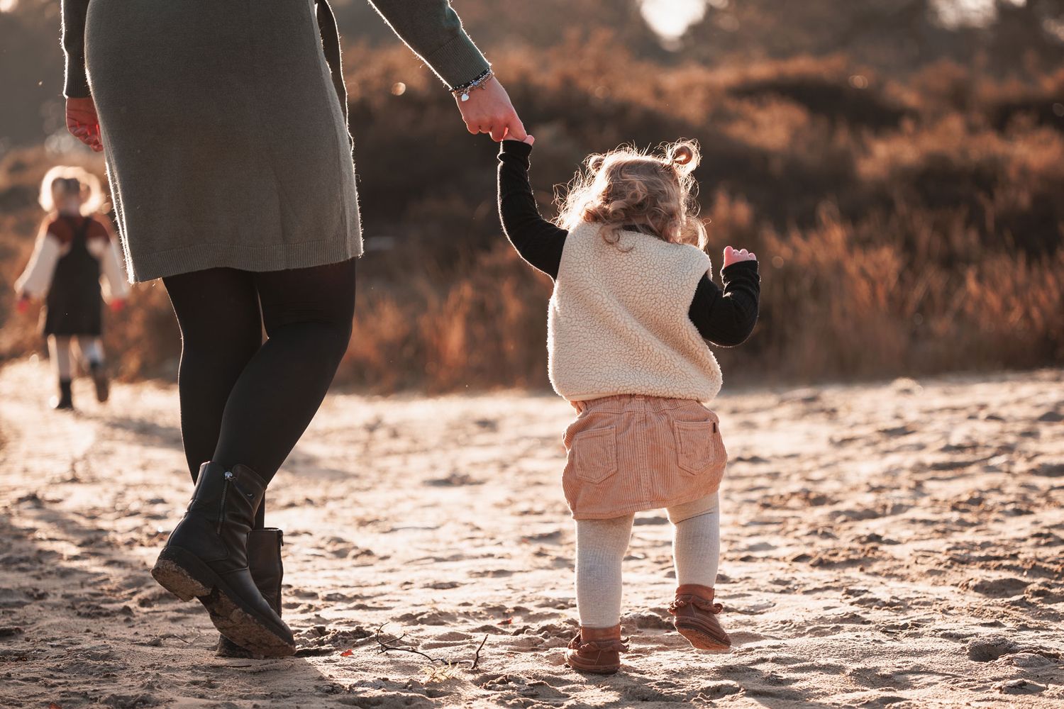 moeder met peuter aan haar hand tijdens gezinsfotoshoot op de heide in Bergen op Zoom