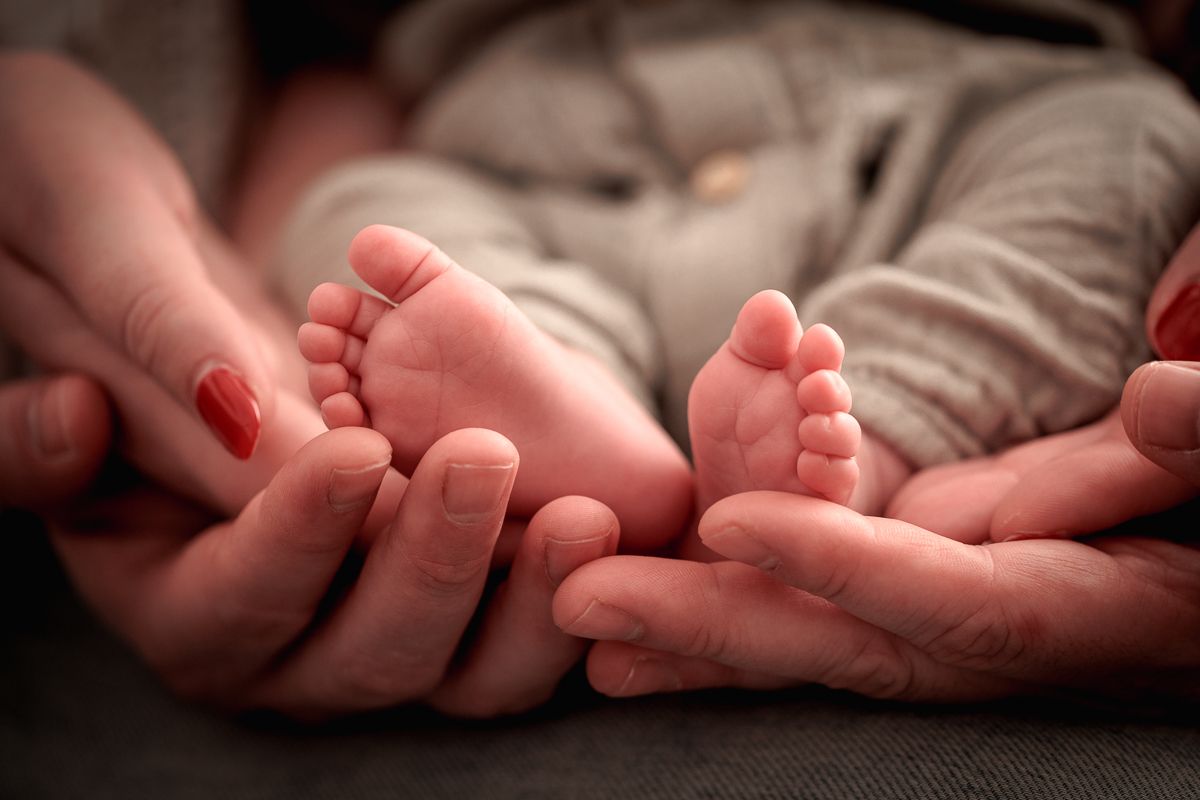 close up van voetjes in de handen van de ouders tijdens newbornfotoshoot thuis