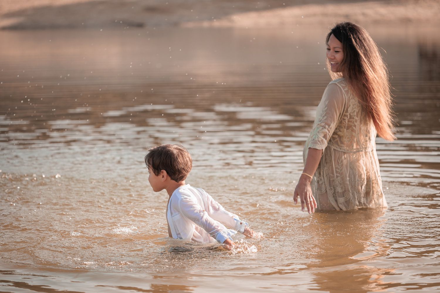 speels moment in het water tussen moeder en kind tijdens fotoshoot bij het water in de zomer