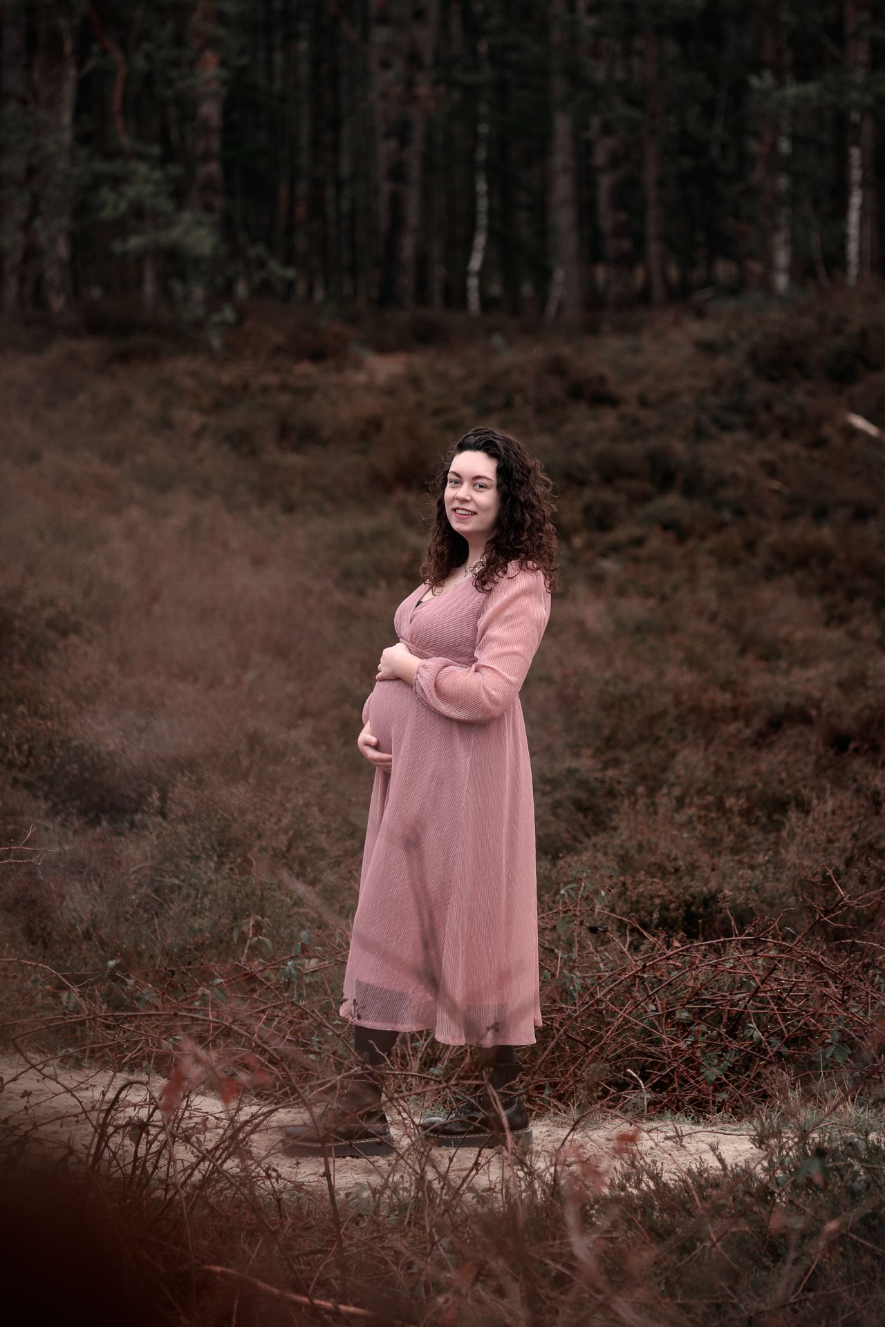 Zwangere vrouw in het bos met jurk aan