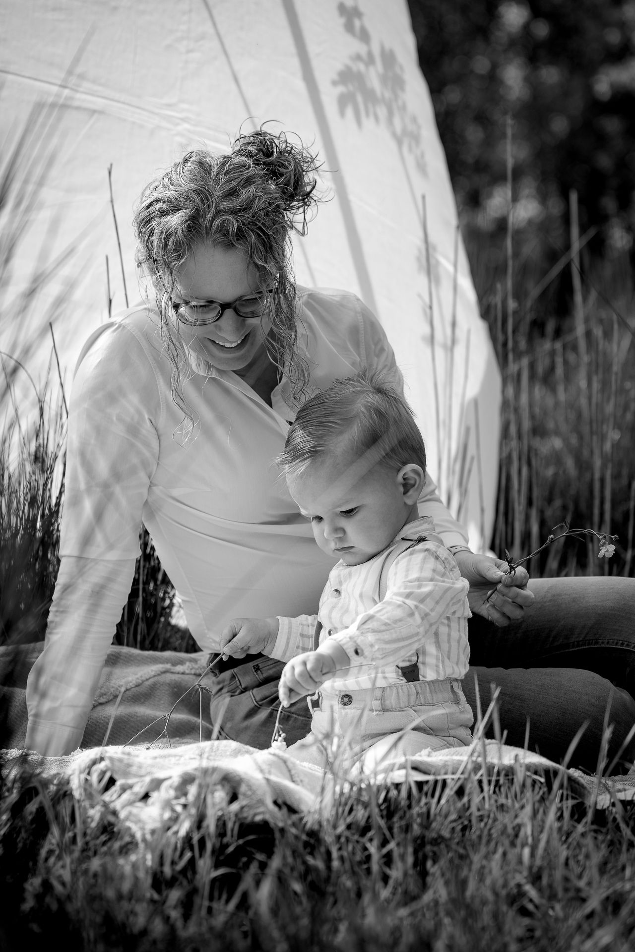 Ongedwongen moment tussen moeder met peuter in het gras tijdens motherhoodfotoshoot in Fijnaart