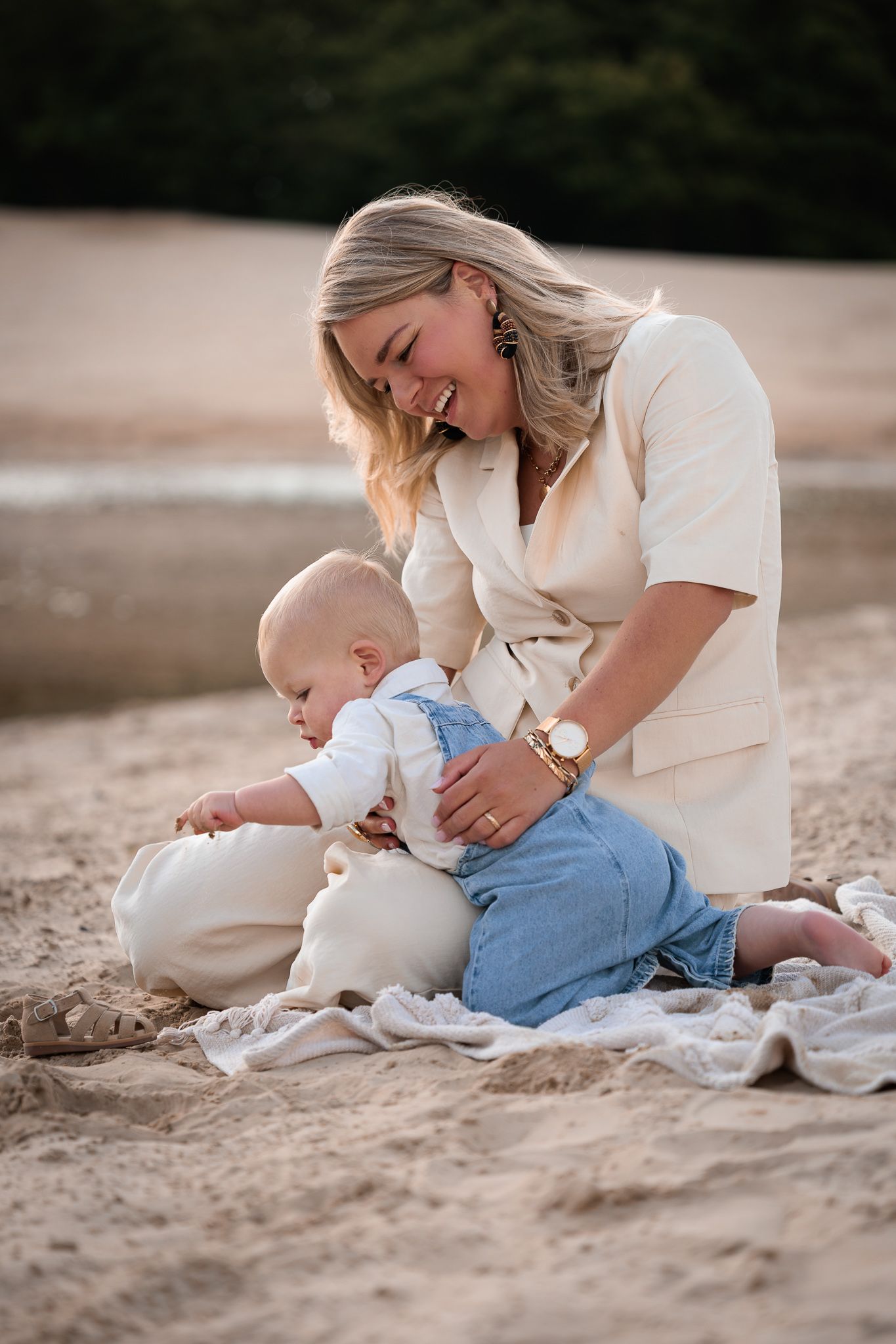 Moeder speelt met haar jonge kind tijdens lieve motherhood fotoshoot op het strand