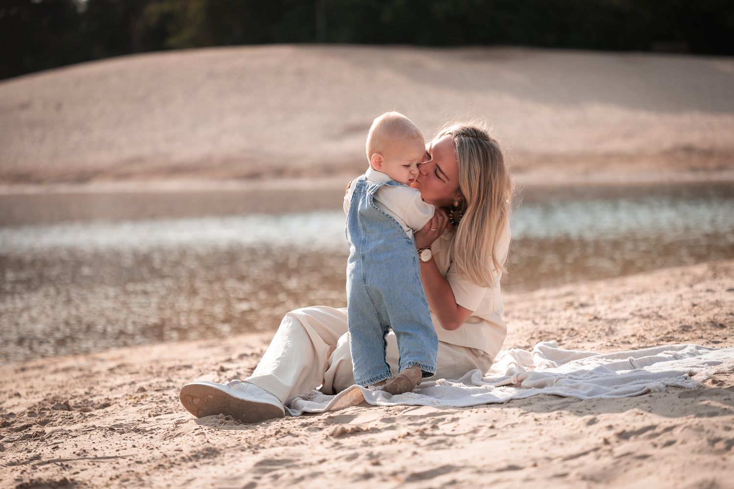 lief intiem moment van moeder en jong zoontje op een kleedje op het zand