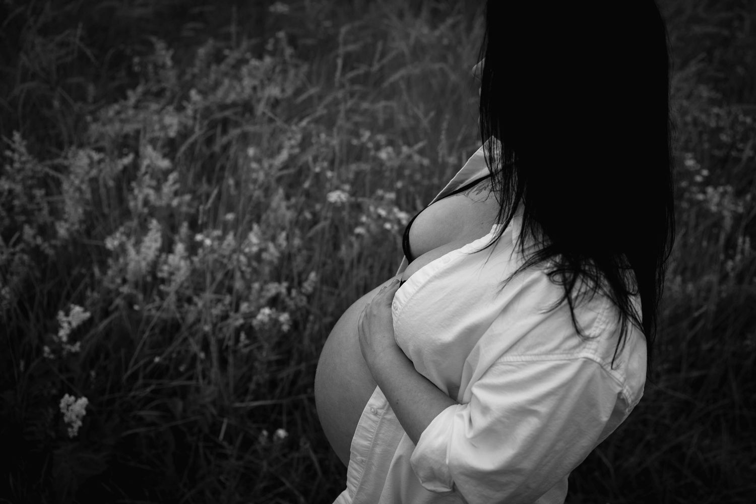intieme foto van zwangere vrouw met open witte blouse in de natuur buiten