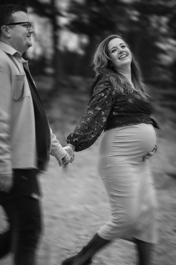 bewogen foto van zwanger koppel, lachend hand in hand