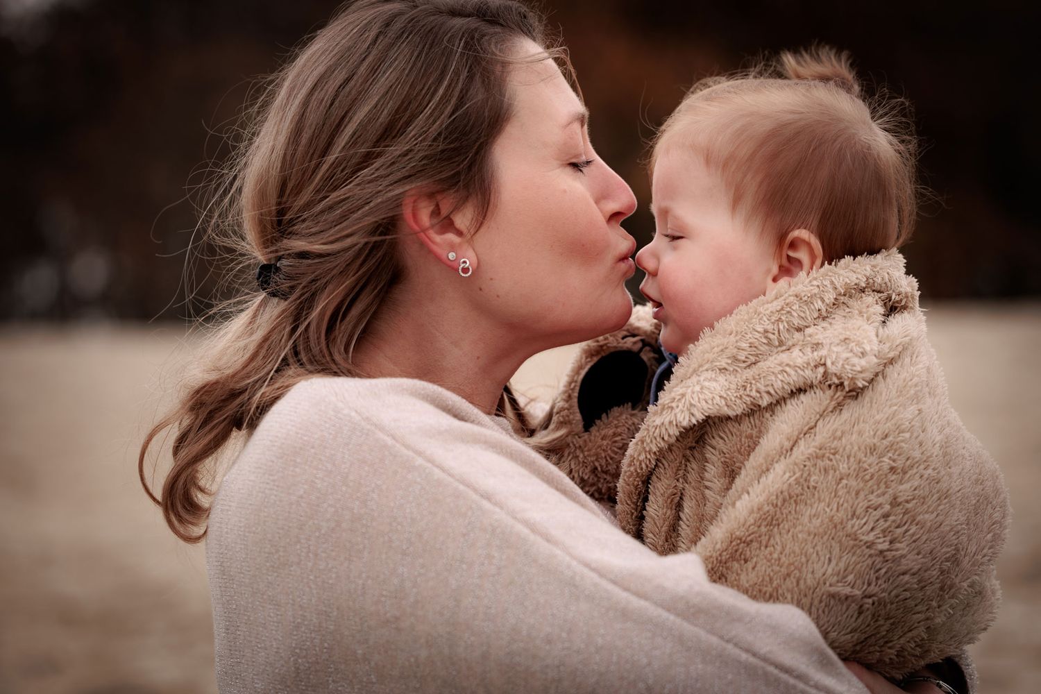 Intiem moment tussen moeder en baby tijdens een motherhood fotoshoot buiten op het strand in Bergen op Zoom
