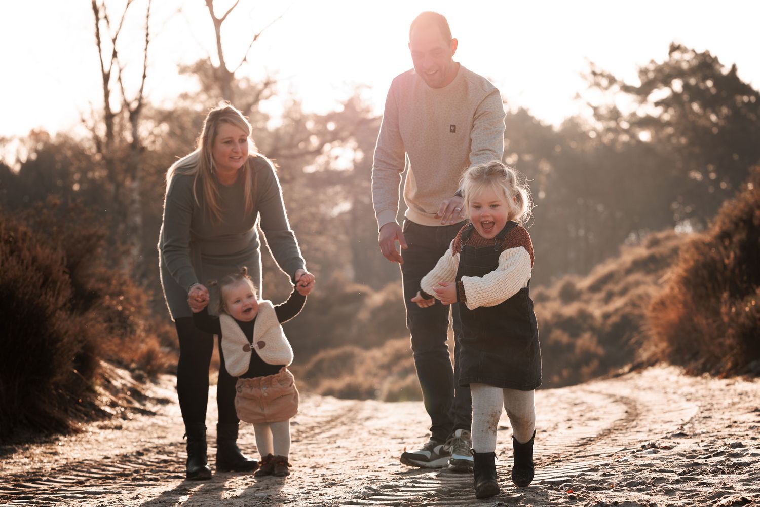 Lifestyle gezinsfotografie met ouders en kinderen samen buiten, liefdevolle familie momentopname door gezinsfotograaf.