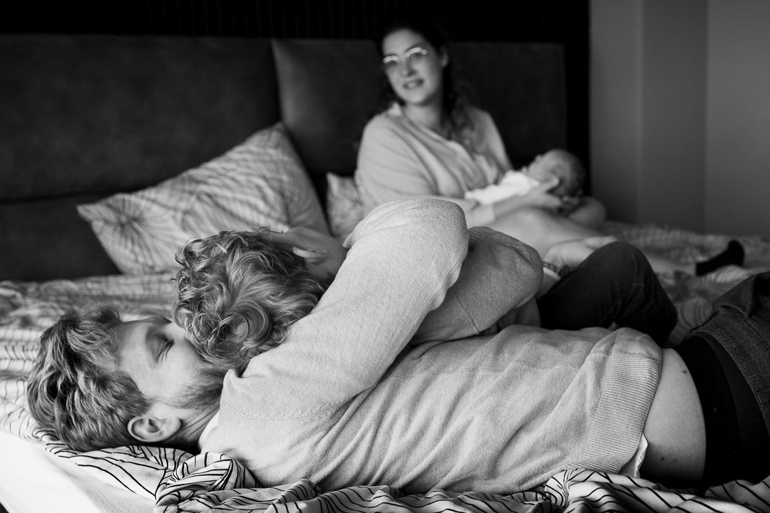 speelse newbornfotoshoot thuis waarbij vader en zoontje stoeien