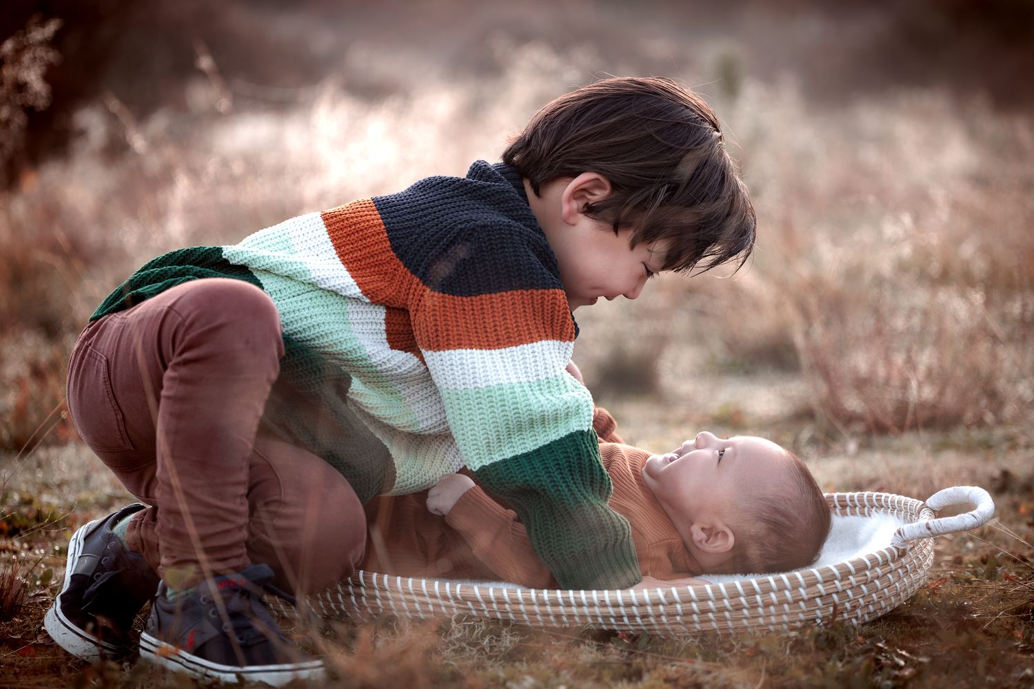 Lief moment tussen babybroertje en peuterbroertje tijdens ontspannen gezinsfotoshoot in de natuur buiten