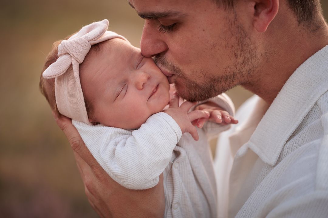 vader die zijn newborn baby optilt en kust met de natuur op de achtergrond