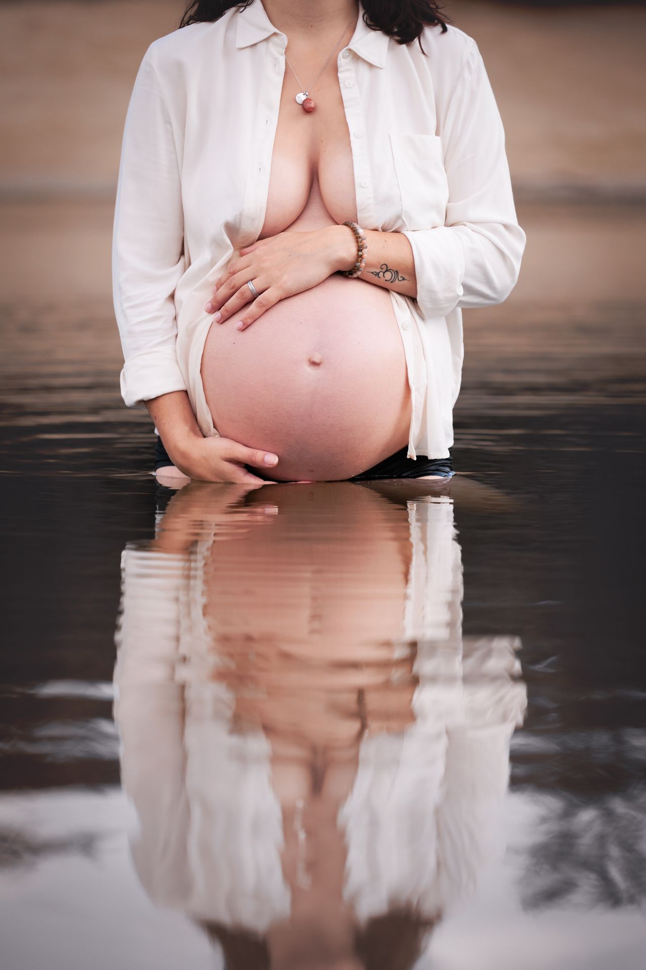 Intieme zwangerschapsfoto in het water met reflectie van de blote buik in het water bij de Bergse Heide in Bergen op Zoom