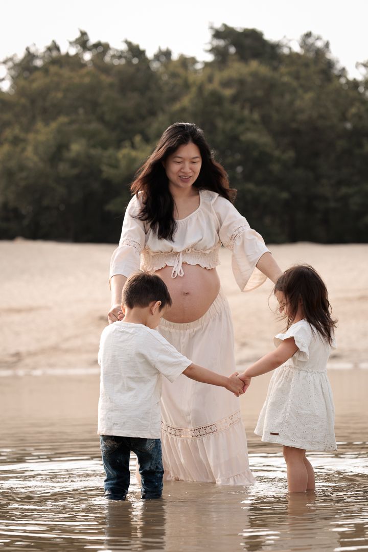 Speelse momenten met zwangere mama en haar kinderen in het water