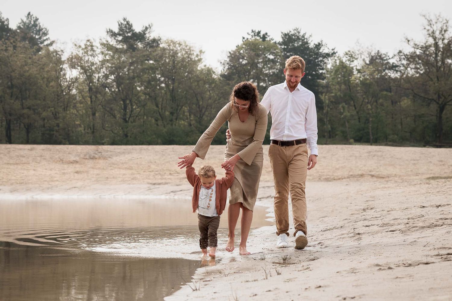 gezin dat door het water loopt tijdens fotoshoot zonder poseren