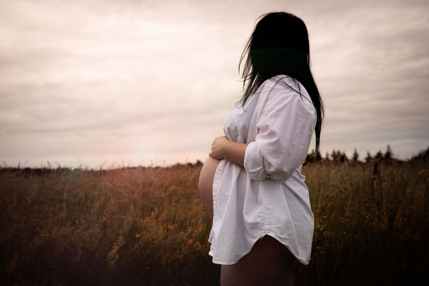 zwangere vrouw in blouse met blote buik gefotografeerd op een buiten locatie in de natuur