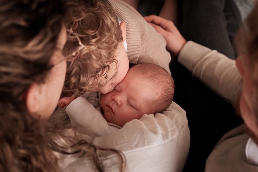 grote broer die zijn newborn broertje een kus op zijn wang geeft