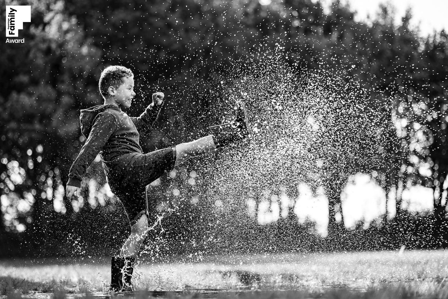 kind met korte broek en regenlaarzen die water schopt, awardfoto van Fotos van Jess, fotograaf in Fijnaart en Bergen op Zoom