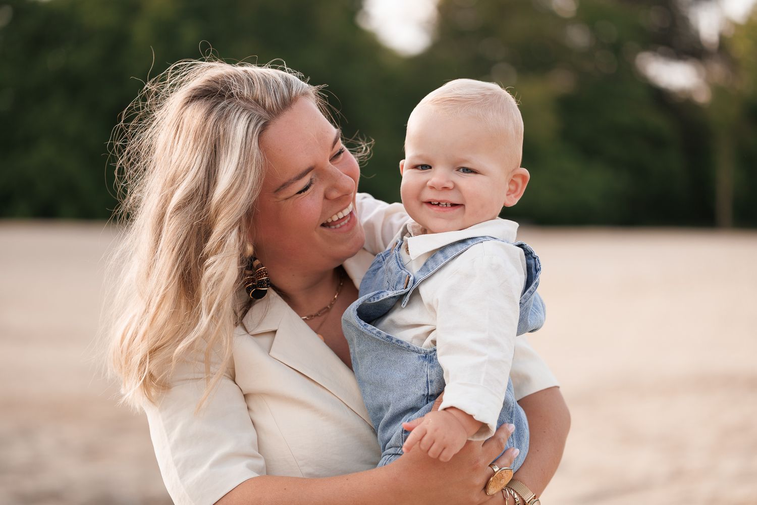 ongedwongen moment van lachende moeder met baby tijdens fotoshoot buiten aan het water