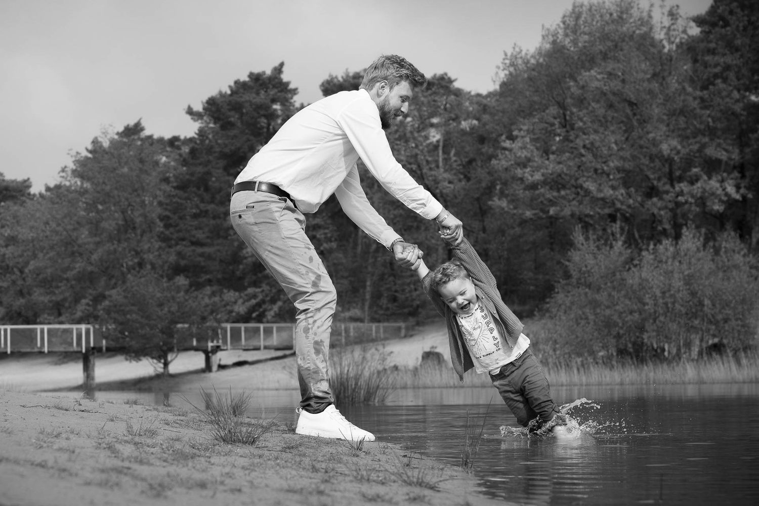 A sequence of black and white photos showing someone performing a front flip into water at a park.