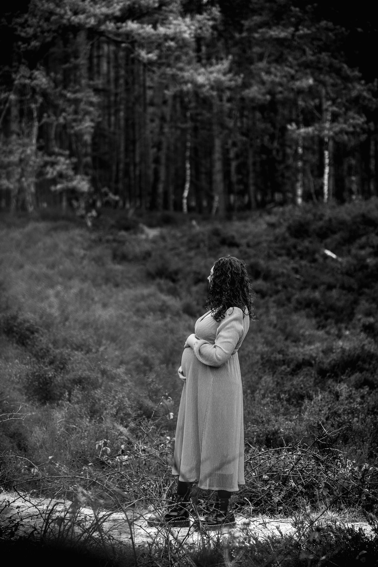 Zwart-wit foto van zwangere vrouw in lange jurk tussen de bomen, het bos en heide in Bergen op Zoom