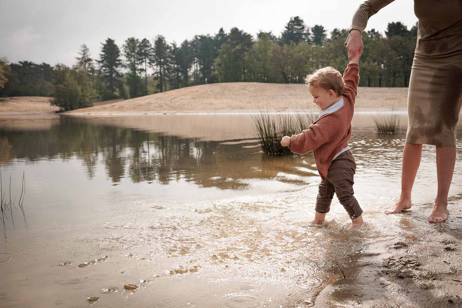 Peuter aan de hand van zijn moeder met zijn voeten in het water bij de Bergse Heide - fotograaf brabant
