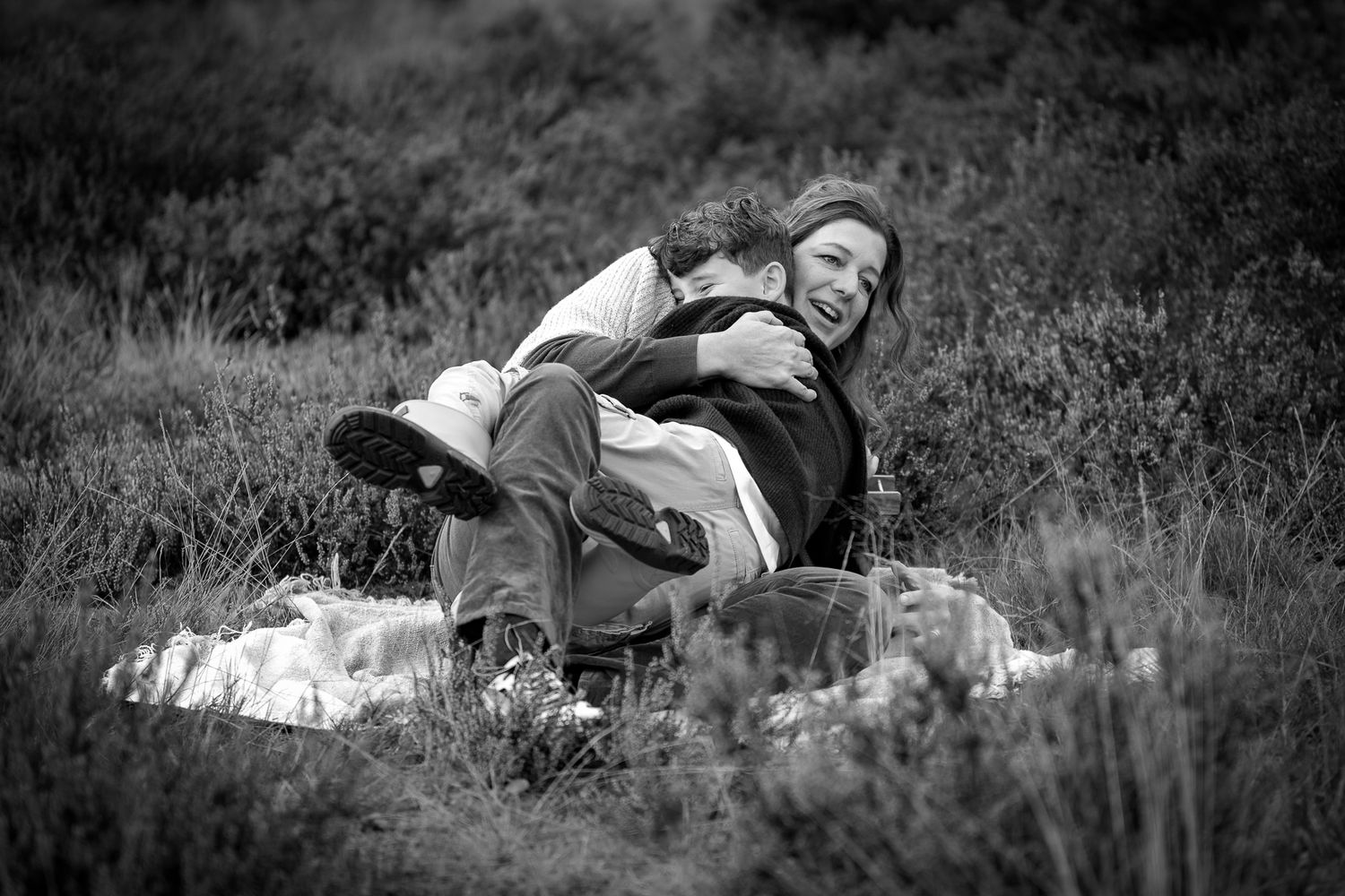 grappig moment tijdens fotoshoot waarbij zoontje zijn moeder zo enthousiast knuffelt dat ze samen omvallen - Gezinsfotograaf bergen op zoom