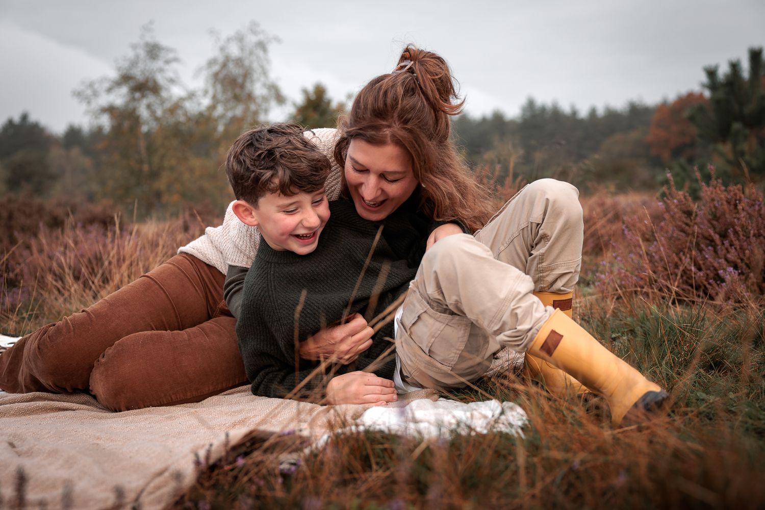 Moeder en kind op een kleedje in het gras tijdens fotoshoot op de heide waarbij echte momenten centraal staan - fotograaf Bergen op Zoom
