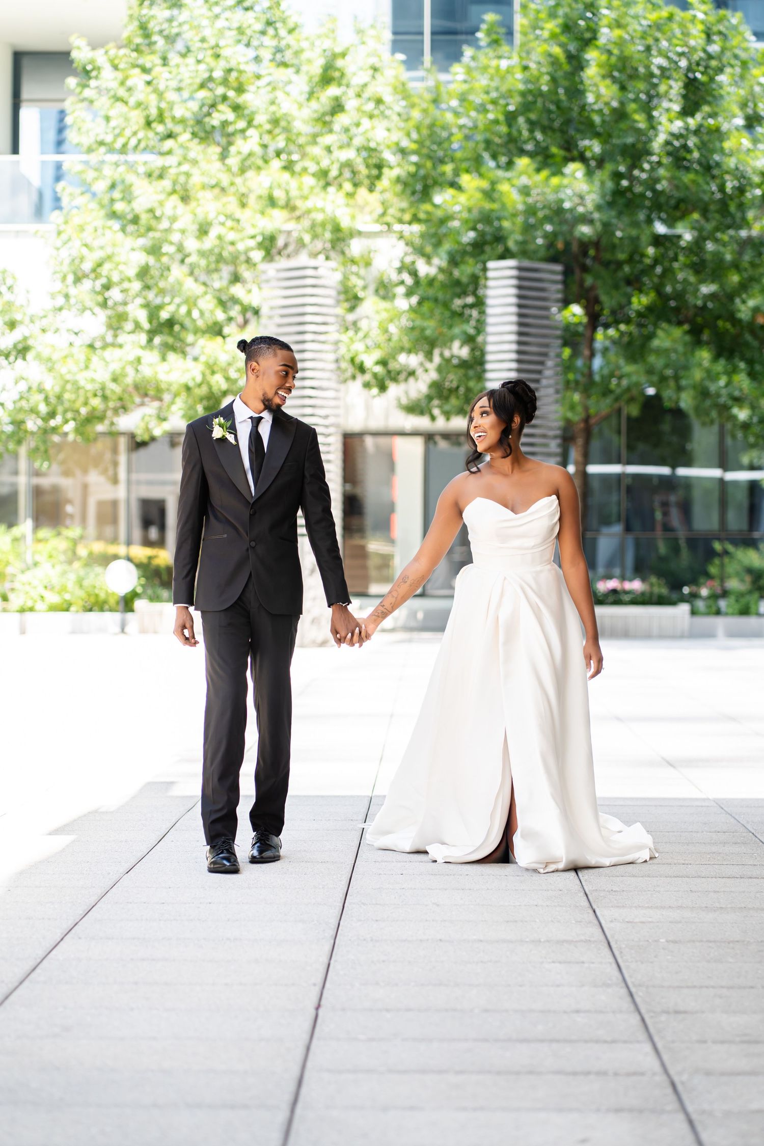 Wedding couple walking together on a bright outdoor plaza.