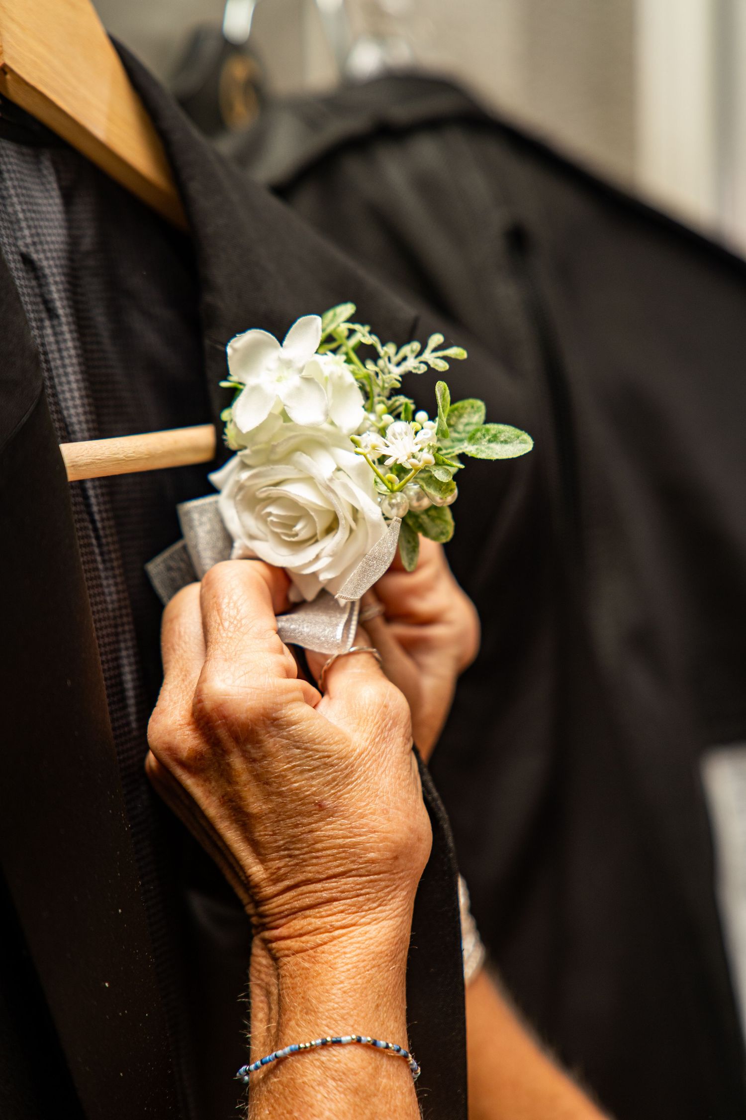 Close-up of white rose boutonniere being prepared for wedding ceremony.