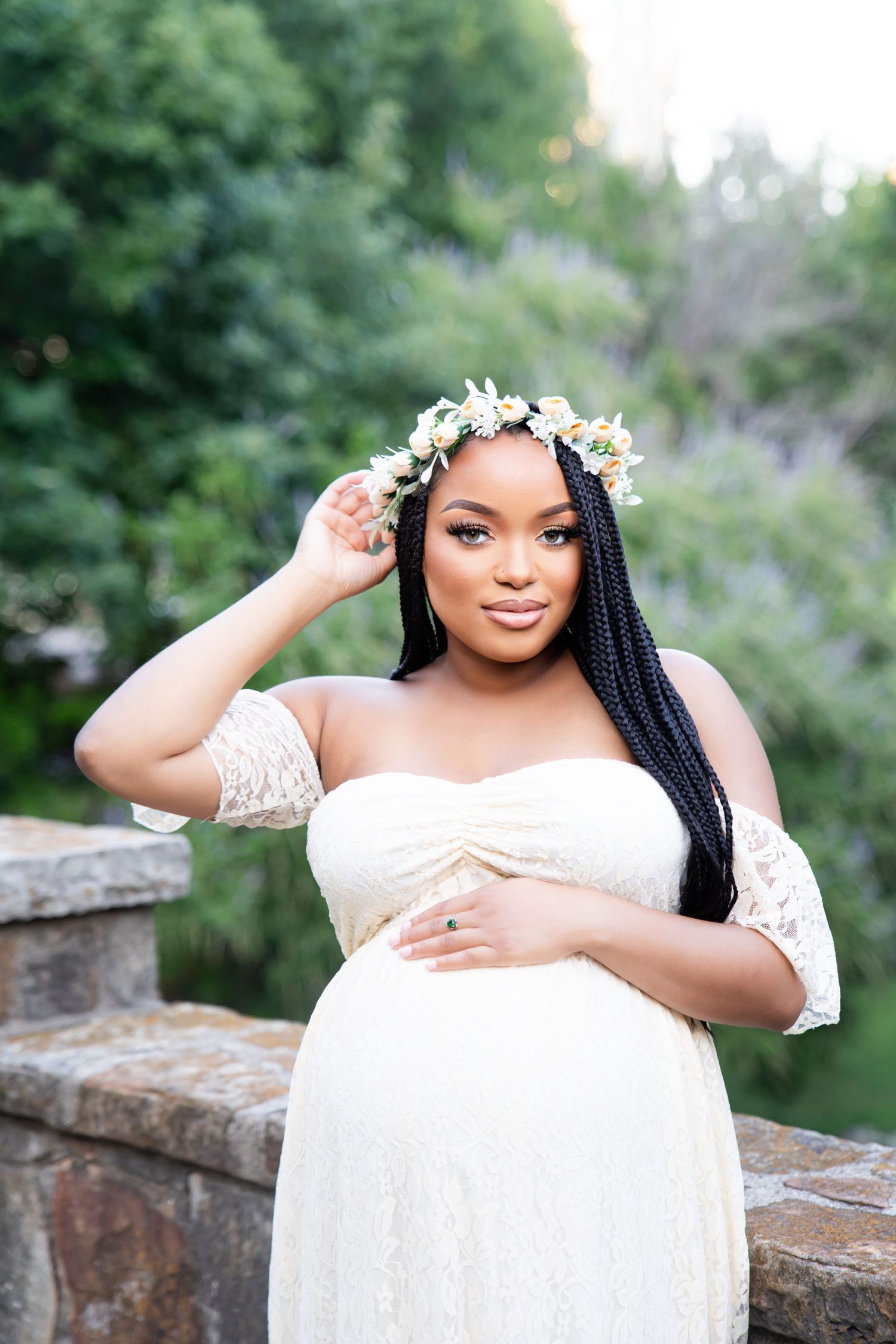 A bridal photoshoot featuring a white lace dress and floral crown against a stone wall backdrop.