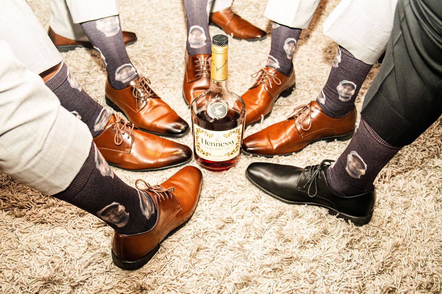 Row of formal dress shoes and boots lined up on sandy ground at wedding event.
