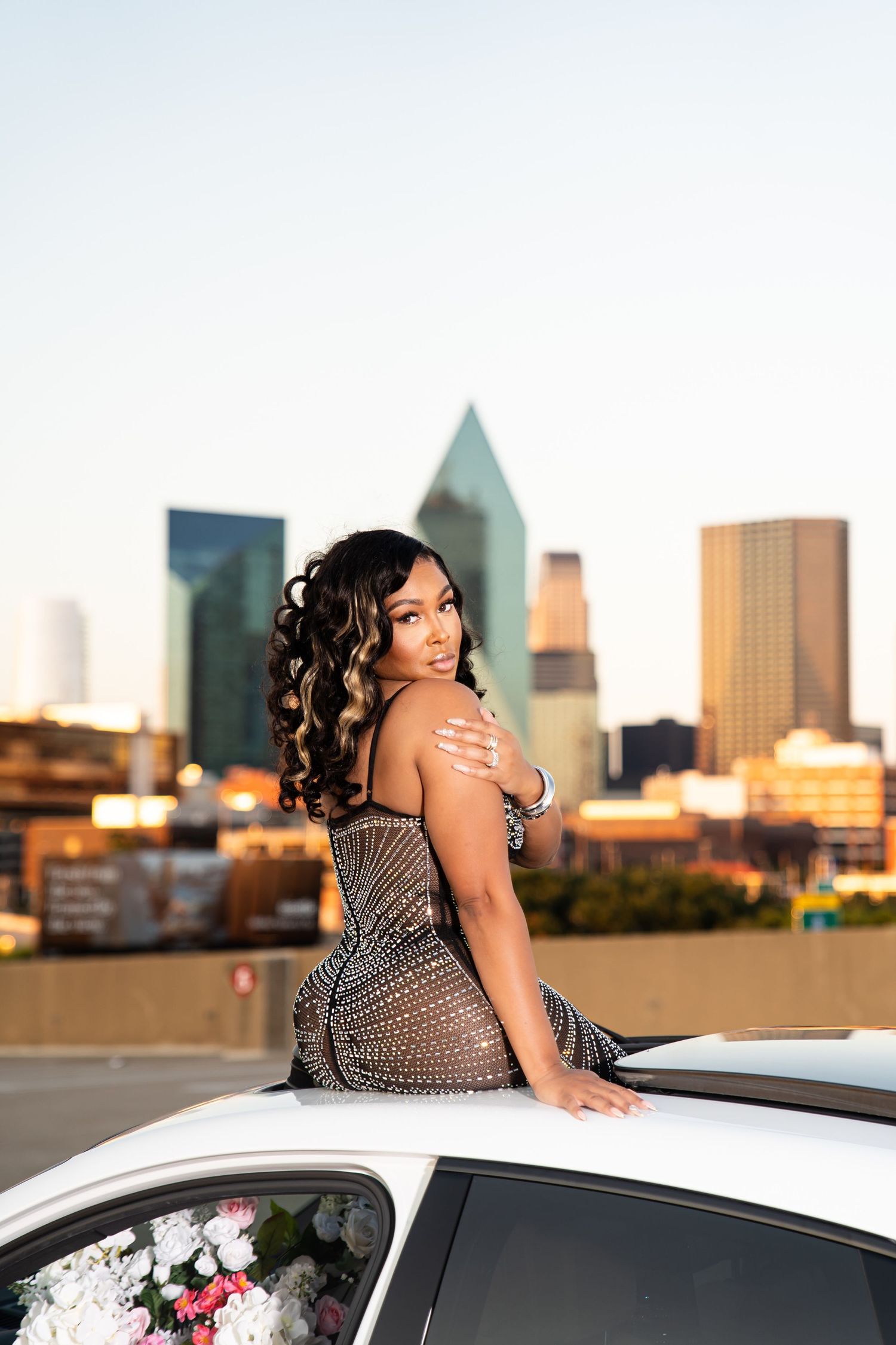 Elegant rooftop photo session with city skyline backdrop and white luxury vehicle.