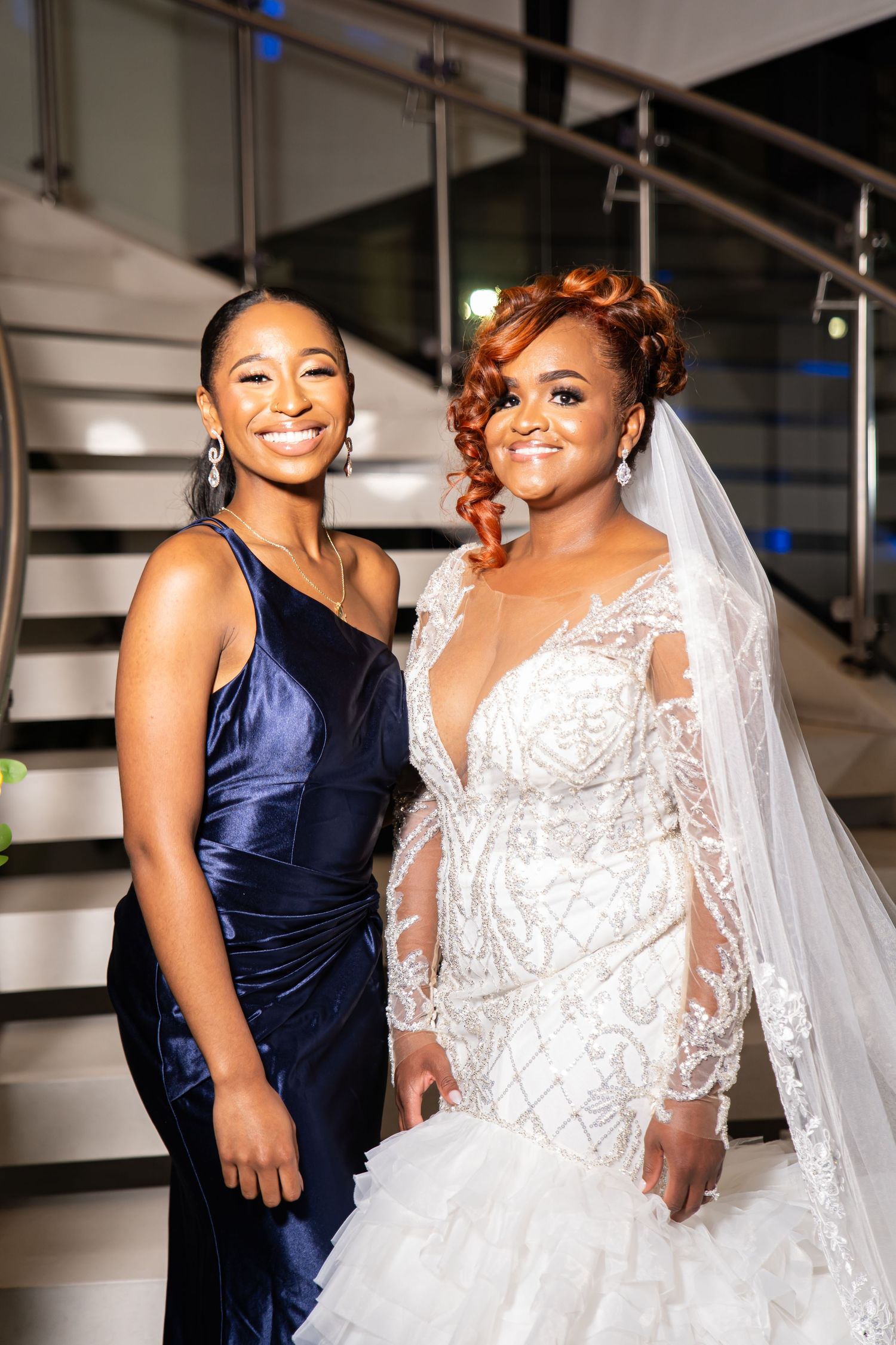 Bridesmaids in navy blue dresses celebrate with bride wearing an ornate white lace wedding gown.