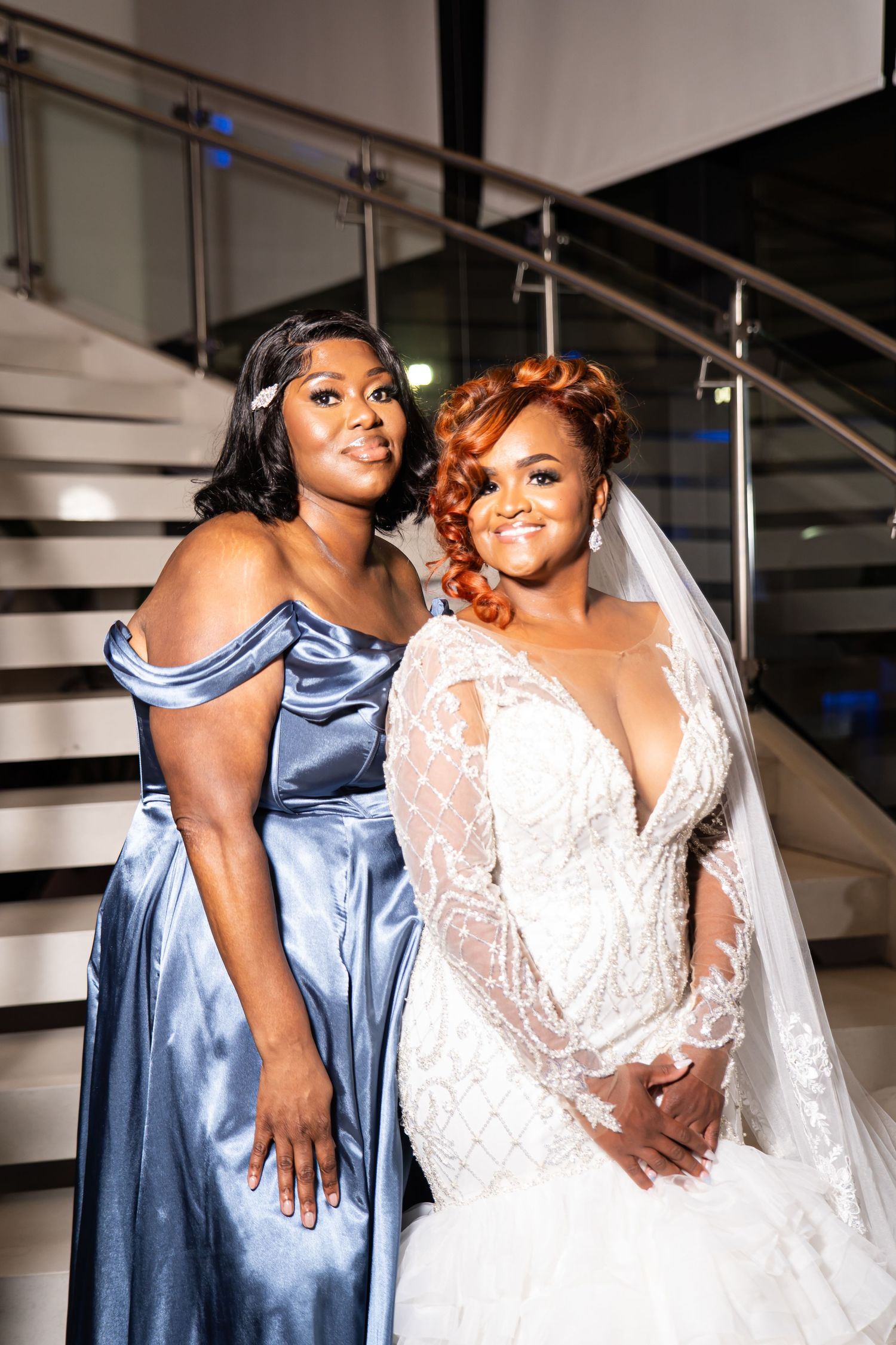 Wedding party members pose together with bride in white lace gown and bridesmaid in navy blue dress.