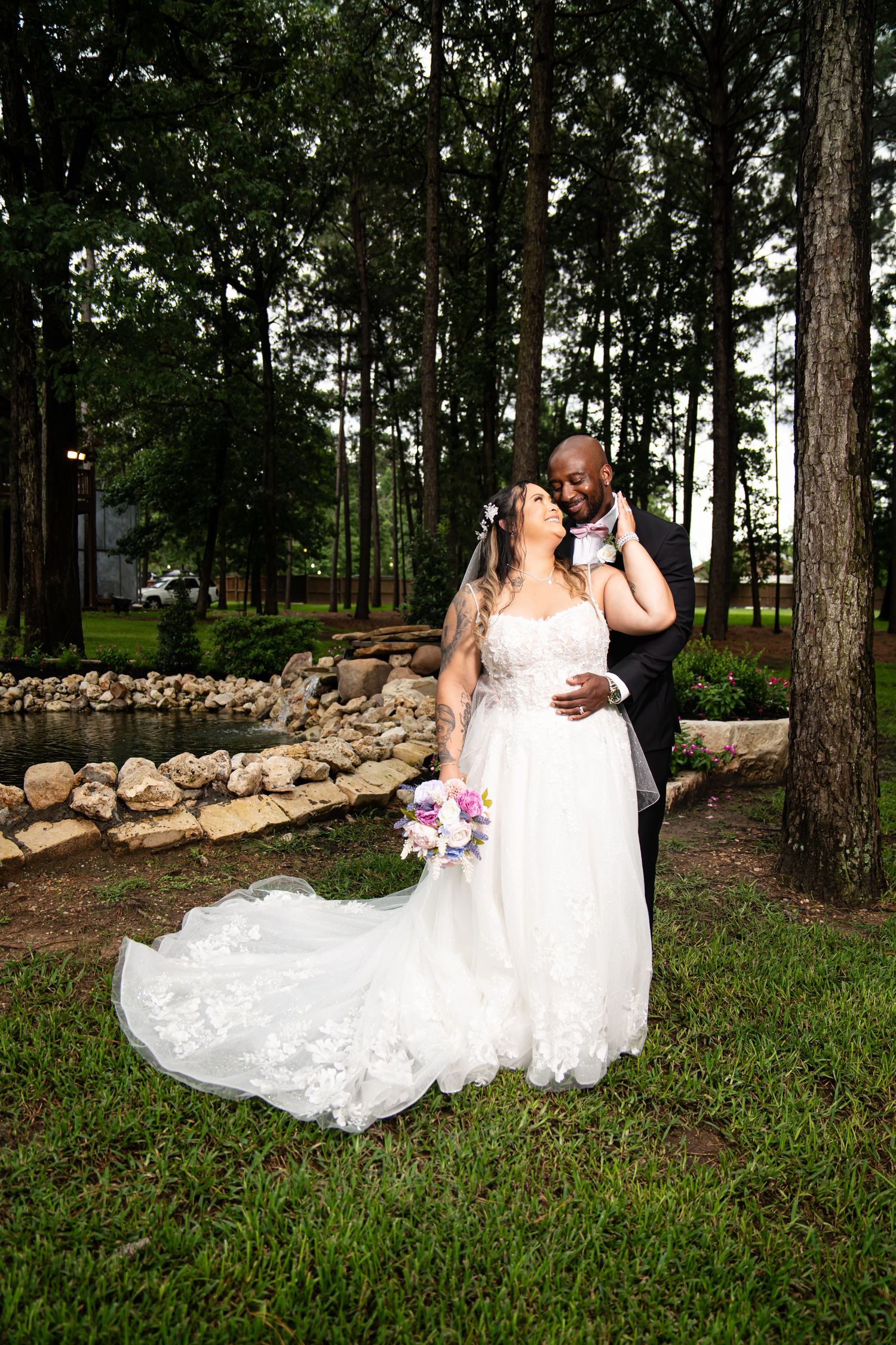 Wedding couple taking romantic photos in a pine forest with stone wall backdrop.