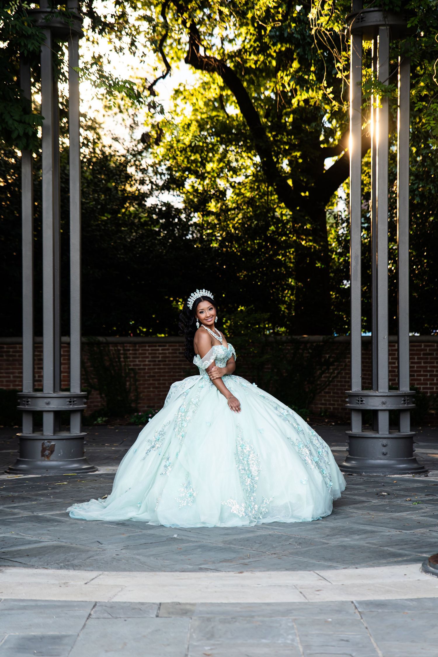 A stunning white ball gown wedding dress photographed in an outdoor setting with white columns and trees.