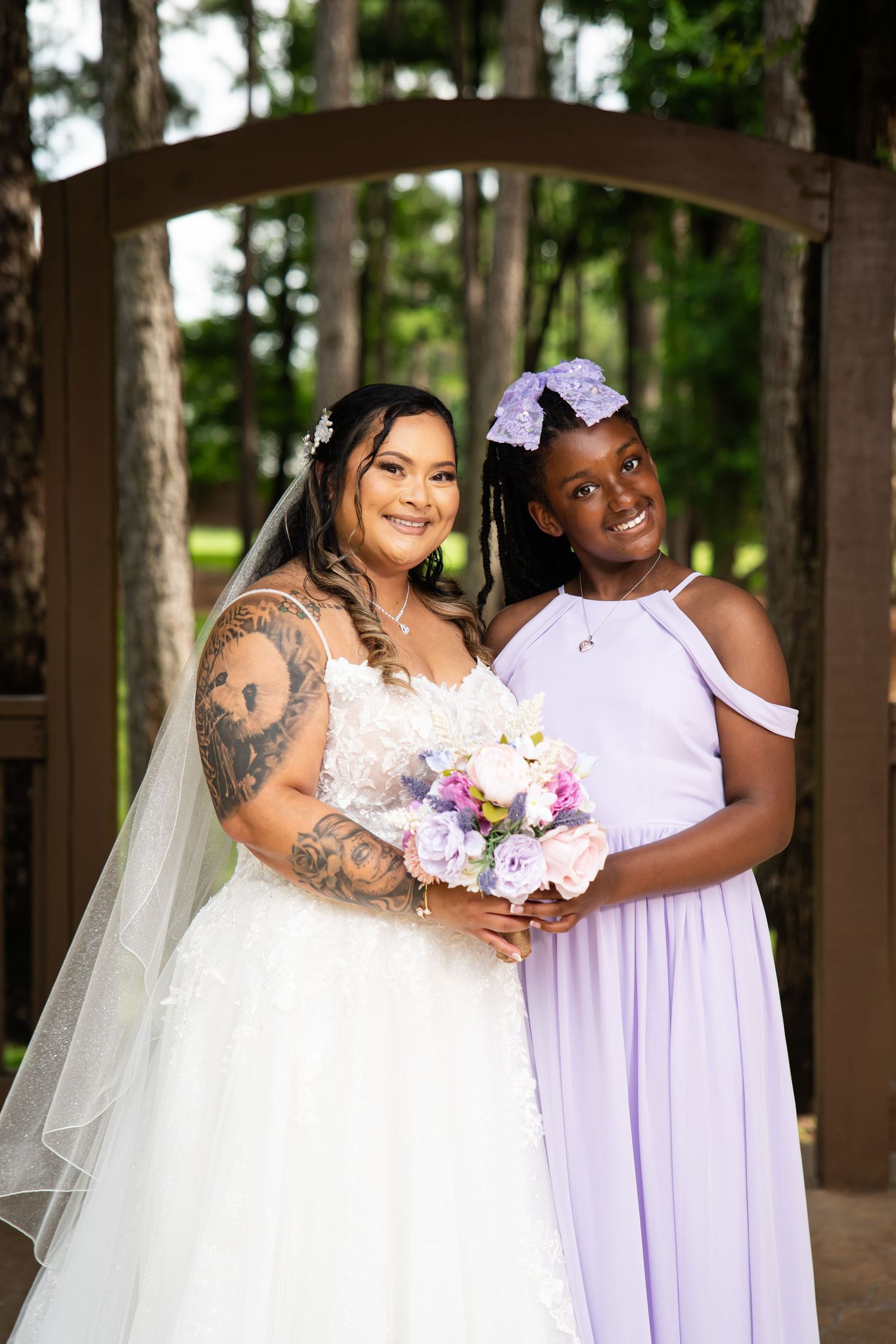 Wedding party members in white and lavender dresses posing together outdoors.