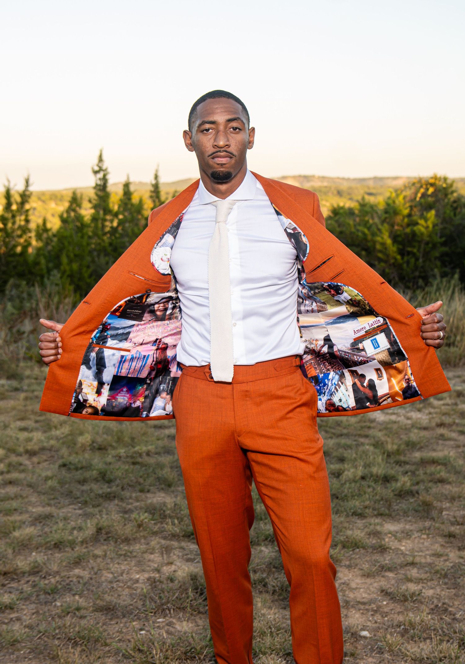 A person in an orange suit shows off their custom photo-lined jacket lining outdoors.